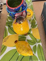 overhead view of mugs stacked on lemon-leaf tray with bird figurines beside