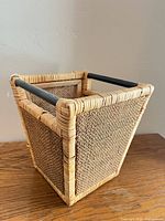 Overall view showing square wicker basket with black handle rods and woven sides