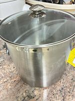 Full view of stainless steel stock pot with glass lid on countertop