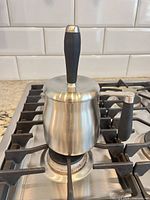 Milk frother on stove showing full exterior, lid and plunger