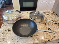 Three pans and two lids on countertop