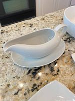 White ceramic gravy boat on matching oval underplate