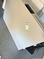 Table folded in half showing white plastic top and auction sticker