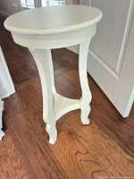 full view of off-white round wooden side table showing legs and stretcher