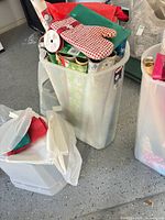 Bin filled with wrapping paper rolls, gift bags, ribbon spool, tissue paper, additional bin nearby
