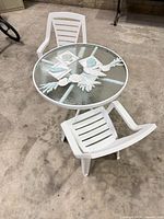Full set showing round glass patio table and two white chairs
