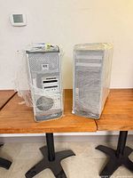 Two wrapped Apple Mac Pro towers front view with mesh panels, optical bays, power cables