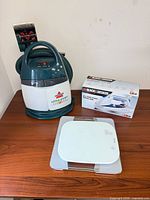 Bissell Little Green cleaner, Taylor kitchen scale, Black & Decker iron box on tabletop
