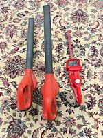 Two blowers and one hedge trimmer laid out on patterned rug