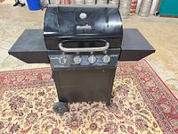Front view of Char-Broil Advantage black 4-burner gas grill with side shelves and wheels