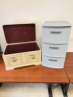 Wooden chest open next to plastic drawer unit