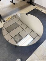 Top view of round mirrored glass table showing reflective surface and thin brass rim