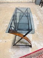 Overall view of desk from front corner showing glass surface, frame and wood supports