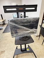 Full view of Perlegear stand with mounted monitor wrapped in plastic