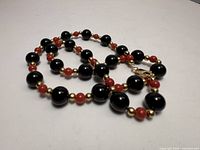 Full view of beaded necklace showing onyx, coral and gold beads