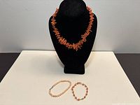 Full lot showing coral branch necklace on display bust with two bracelets below
