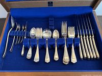 Open wooden chest showing complete 41-piece flatware set in blue lining