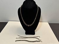 Full view necklace on bust with three bracelets laid flat