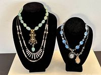 Two bust displays showing all four necklaces layered