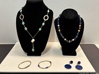 Entire lot displaying two necklaces on stands, two bracelets, pair earrings