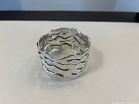 Perspective view of sculptural sterling silver bracelet showing wavy cut-out design