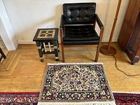 Overall view of chair, side table and Persian rug on hardwood floor