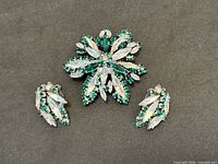 Front view of brooch and earrings showing green and clear navette rhinestones