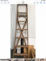 Full view of tall wooden folding ladder leaning against wall