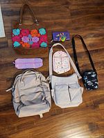 Group shot of all seven bags and accessories laid on wooden floor