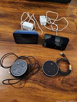 All four Amazon devices laid out: two Echo Show 5 units with adapters, two Echo Dot 2nd Gen units with cables