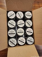 Open cardboard shipping box showing 12 Malicious Women Co. soy candles neatly packed