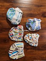 Five diaper covers laid out to show patterns and closures