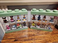 Both green-topped LEGO display cases showing 16 Disney minifigures