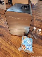 Frigidaire mini fridge front, two glass bottles, bag of snack cups