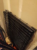 Crate folded flat leaning against wall, shows wire construction and hinges