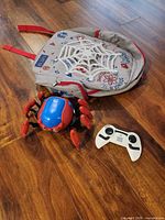 Spider-Bot, remote controller and backpack on wood floor