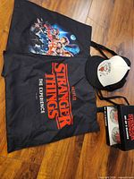 Lot overview showing two tote bags, Hellfire Club hat, boxed glass set