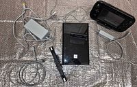 Full lot showing console, GamePad, two power adapters, sensor bar, AV cable, stand