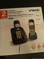Front of box showing two black handsets and answering base, product branding and features
