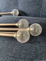 Four glass globe finials attached to brushed silver rods
