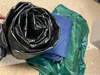 Rolled black mattress with folded blue and green mattresses