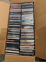 Top-down view of full carton showing approximately 100 jewel case CDs stacked vertically