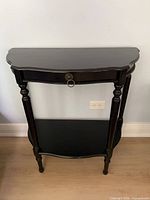 front view of black demilune console table showing drawer and shelf