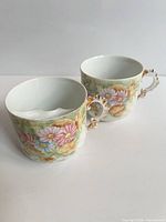 Pair of floral porcelain teacups showing exterior design and handles