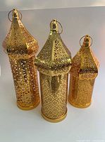 Front view of three gold-tone metal lanterns