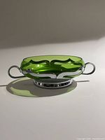 Oblique view showing green glass bowl in chrome holder with handles
