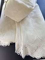Folded pair of ivory lace panels showing scalloped bottom edge and rod pocket top