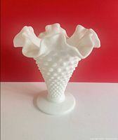 Front view of white milk glass hobnail vase showing ruffled rim and pedestal base