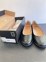 Pair of black ballet flats beside original Naturalizer box