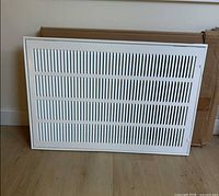 Front view of white EZ-Flo return grille leaning against its box